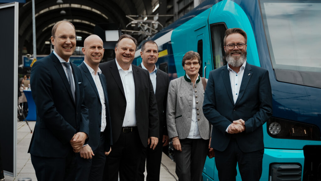 In Schleswig-Holstein geht die erste Akku-Triebzug-Flotte in Betrieb. Zu sehen sind NAH.SH, Ministerpräsident und Stadler