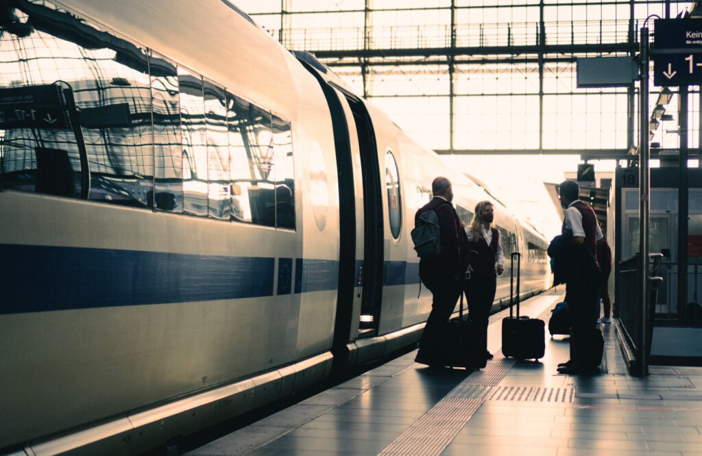 IDE mit DB Mitarbeitern und Fahrgästen am Bahnhof als Bild für den DB Fahrplan 2024
